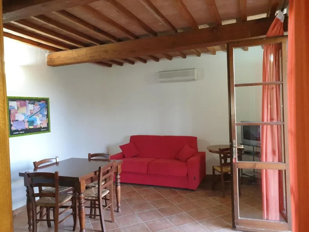 toscaanse-kust-borgo-di-montemurlo-bilocali-classic-woonkamer-met-rode-bank-en-eettafel-022-casamia