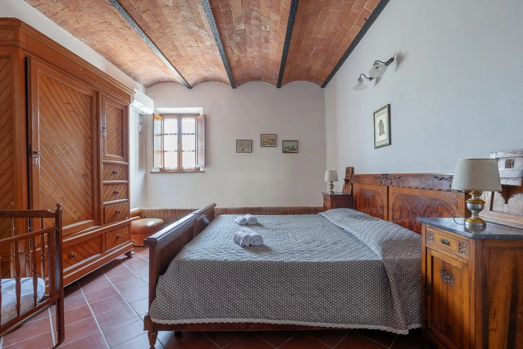 toscane-il-gattero-rosa-slaapkamer-met-houten-balkenplafond-casamia